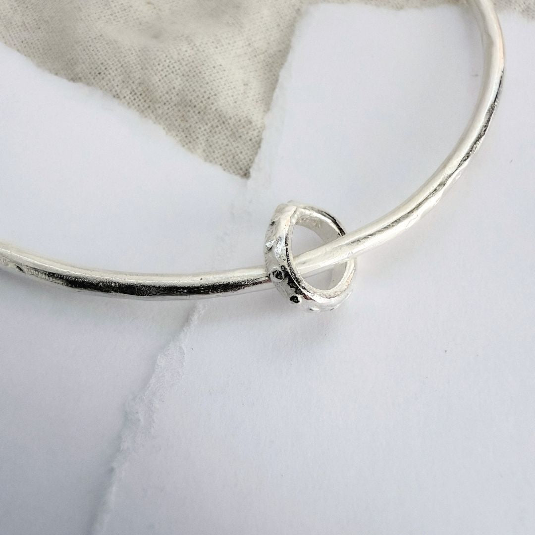 Close-up of the sculpted Fluid ring detail on an organic satin-finish sterling silver bangle