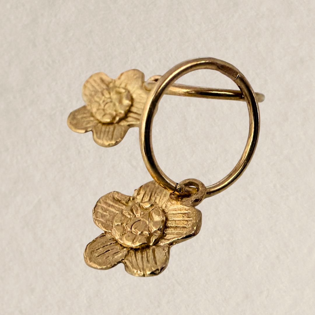 Close-up shot highlighting the detailed petal texture and craftsmanship of the 18ct gold-plated daisy charm on a sleeper hoop.