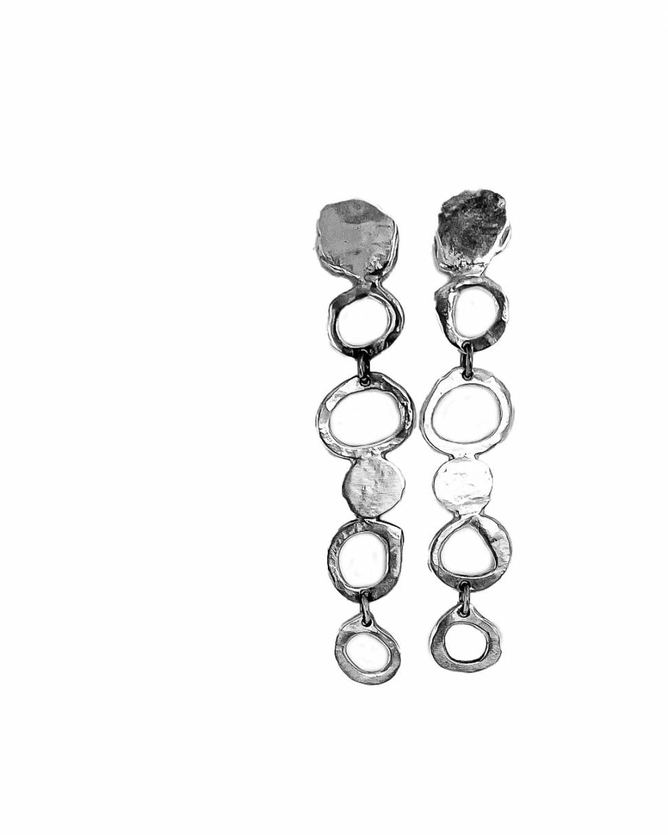 Showing the front of a pair of contemporary-designed drop earrings are inspired by the graceful fall of raindrop in Sterling Silver showing the organic texture of the earrings