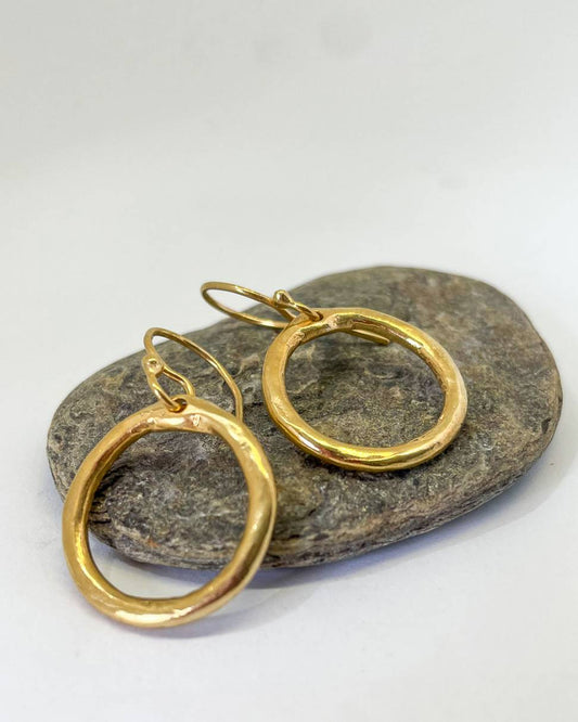 A pair of 18ct Gold plated organic Circle hoop earrings lying on a stone 