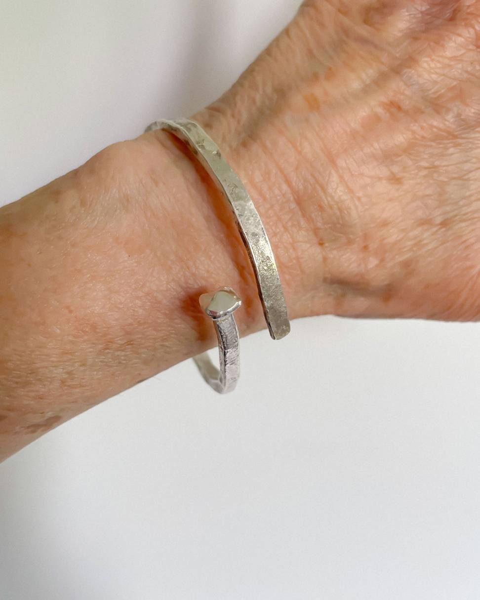 A close up image of the Sterling Silver Sheet Cut Nail Cuff showing the cross over style worn on a female model