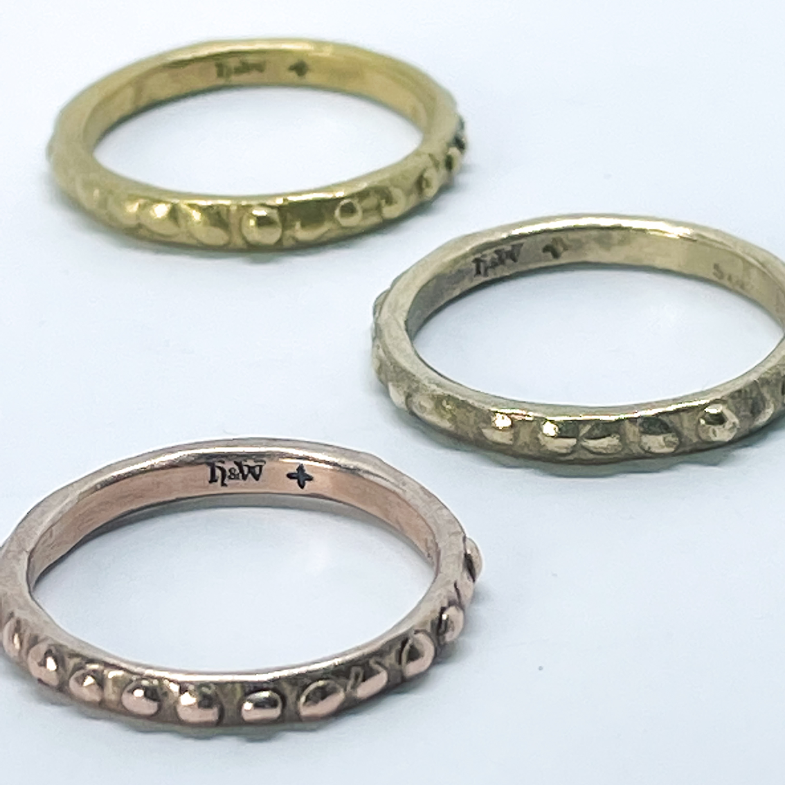 Three narrow textured stacking rings one is 9ct Rose Gold, the second is 9ct yellow gold and the back ring is 18ct yellow gold