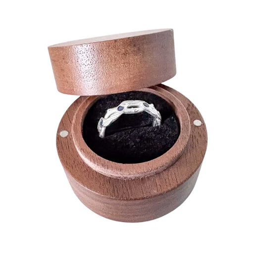 Sterling silver pōhutukawa ring with blue sapphires displayed in round wooden ring box