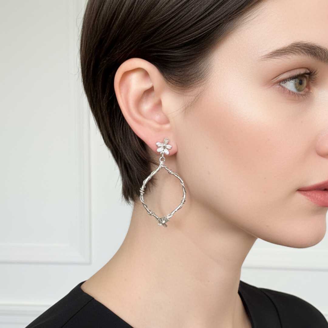 Woman wearing handcrafted sterling silver interwoven flora statement earrings in an indoor setting- New Zealand made botanical jewellery