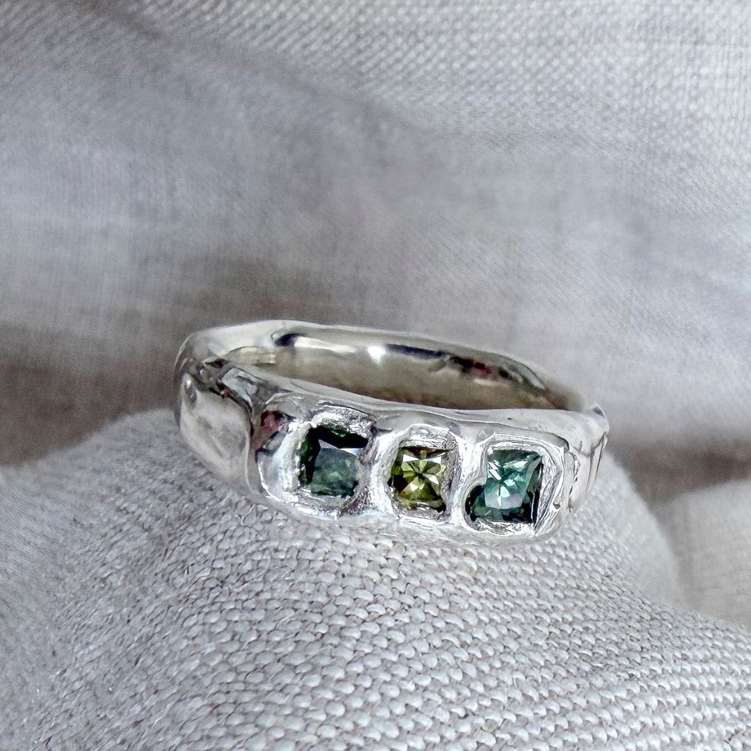 Kākāriki sterling silver signet ring with three square green sapphires in varying shades, set into an organic, softly polished silver band.