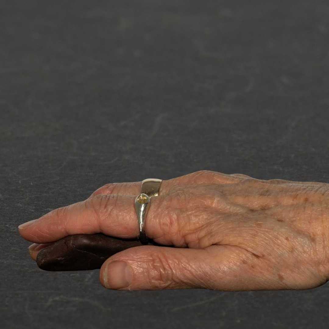 Handcrafted Kowhai sterling silver signet ring with a natural pear-cut citrine gemstone being worn on a finger, showcasing artisan jewelry design.