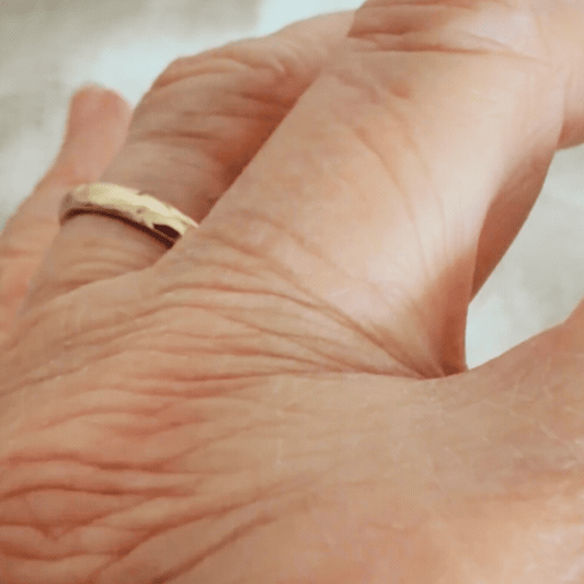 Handmade 9ct yellow gold Molten Ring shown on the hand in motion, revealing its uneven contours, textured surface and warm gold finish.