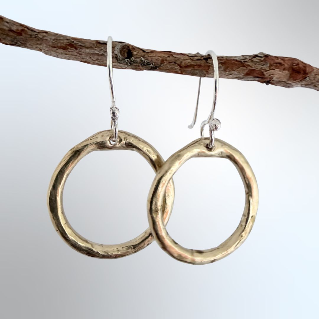 Organic Circle Hoop Earrings in bronze hanging from a branch, light grey-blue background — HerbertandWilks