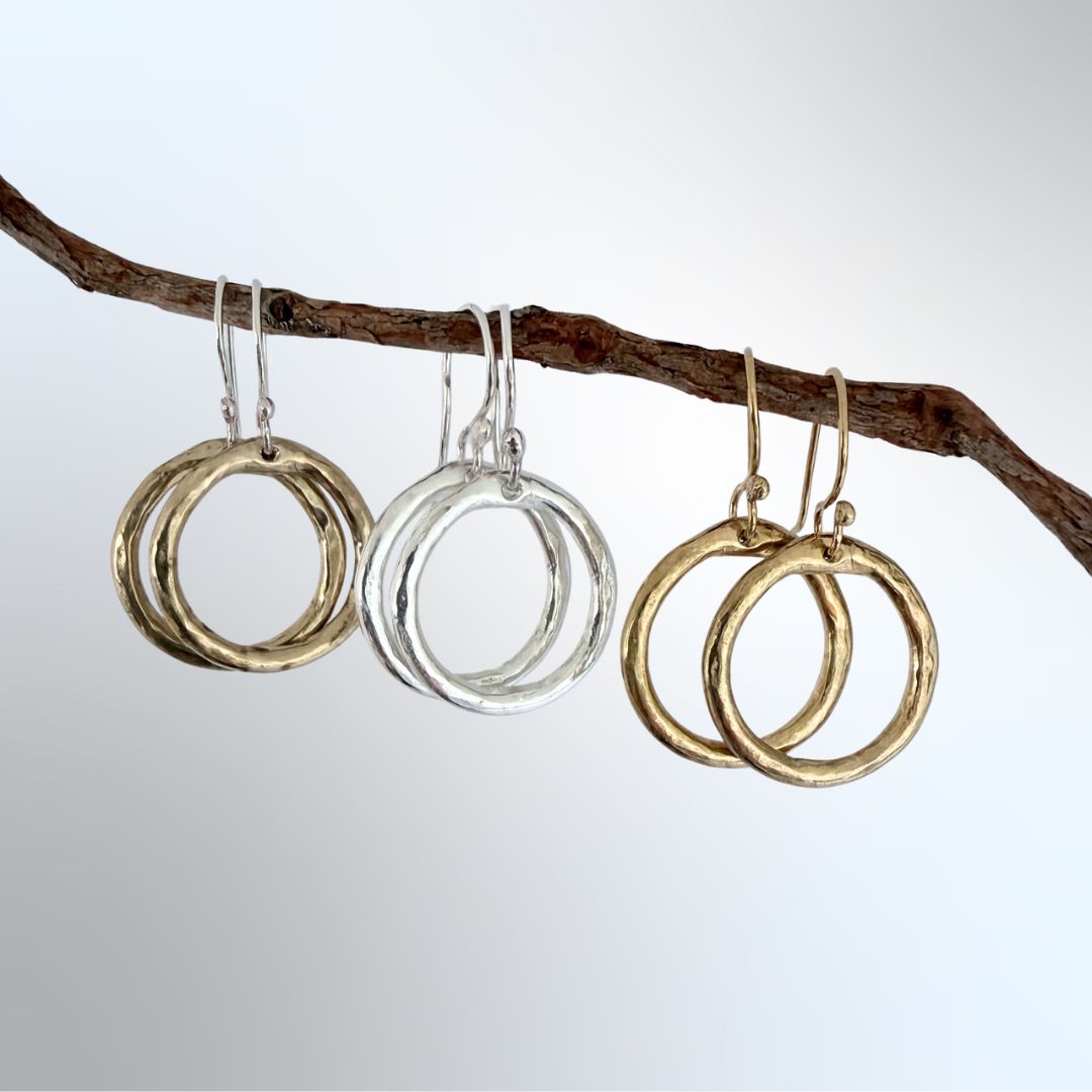 Three Organic Circle Hoop Earrings in sterling silver, 18ct gold plate, and bronze hanging from a branch — HerbertandWilks