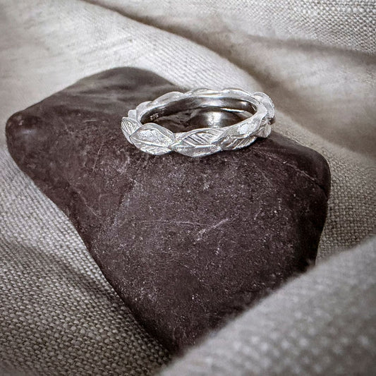 Sterling silver Organic Leaf Stacking Ring displayed on a dark stone, showing the sculptural overlapping leaves around the band.
