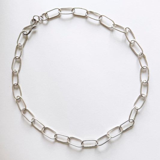 Handmade sterling silver Oval Link Chain necklace with 20mm elongated links, satin-polished finish and handcrafted hook clasp, laid flat on white.