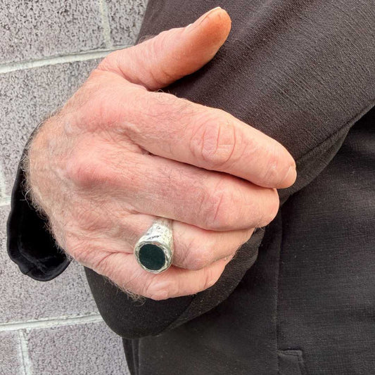 Oval Bloodstone Signet Ring worn on [index/ring] finger, arms crossed, showing how the oval face sits across the finger in landscape orientation — HerbertandWilks Jewellery