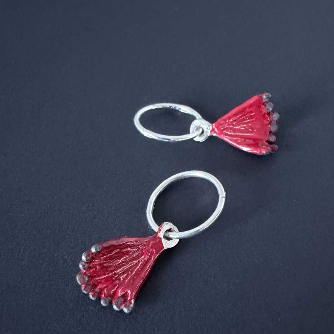 Full set of Pohutukawa charm earrings: two red enamel and sterling silver flower charms hanging from 12mm silver sleeper hoops.
