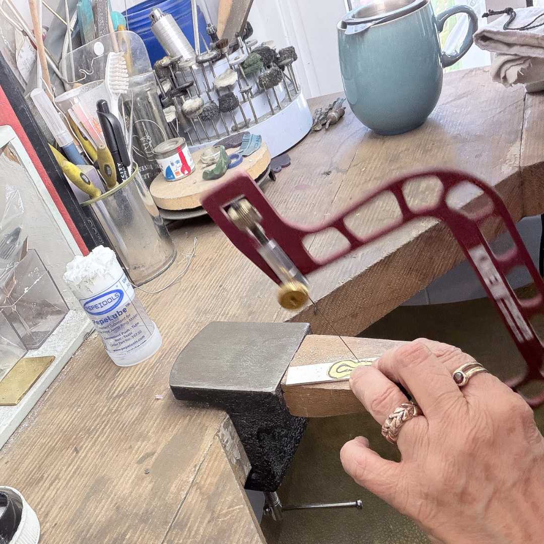 Sterling silver ring being sawn out by hand around the split ring design during workshop process