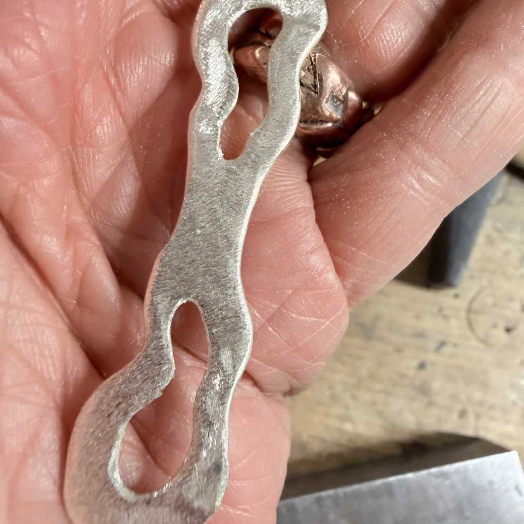 Close-up of textured sterling silver split ring showing cut-out sections and solid band for back of finger
