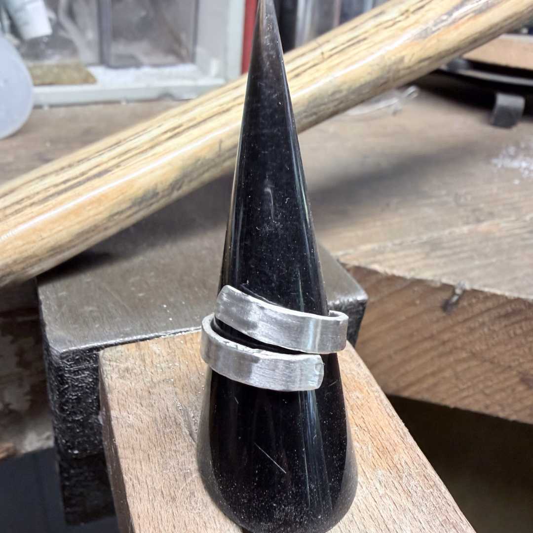 Solid sterling silver open ring displayed on a dusty black ring display sitting on the wooden bench pin in the HerbertandWilks Studio in Mt Eden