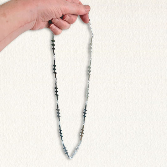 Long sterling silver Talisman Necklace held by hand to show its 70cm length and scale.