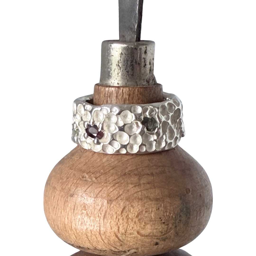 Close-up of Trace Ring showing organic crater texture and cast-in-place sapphires on jeweller’s graver