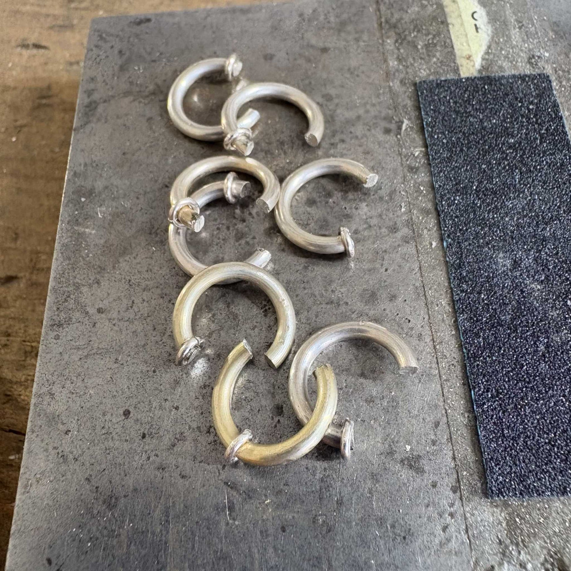 In-progress view of Wrapped Hoop Earrings, showing sterling silver hoop with small jump rings used to secure the bead and form the distinctive end.
