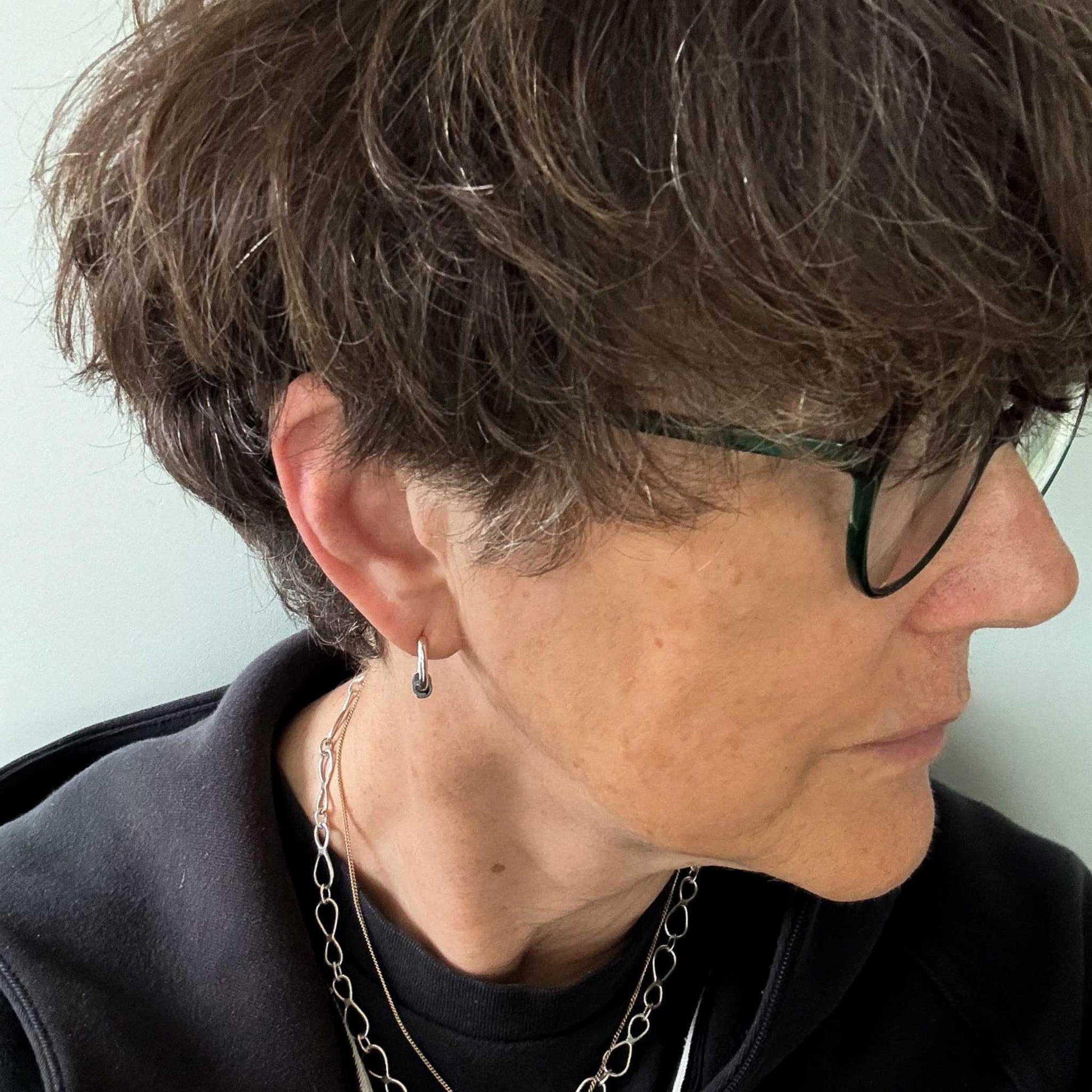 A woman with short brown hair wearing the Wrapped  Hoop Earrings with Fine Silver Keum Boo Beads against a light background. Shows the size of the hoop earrings