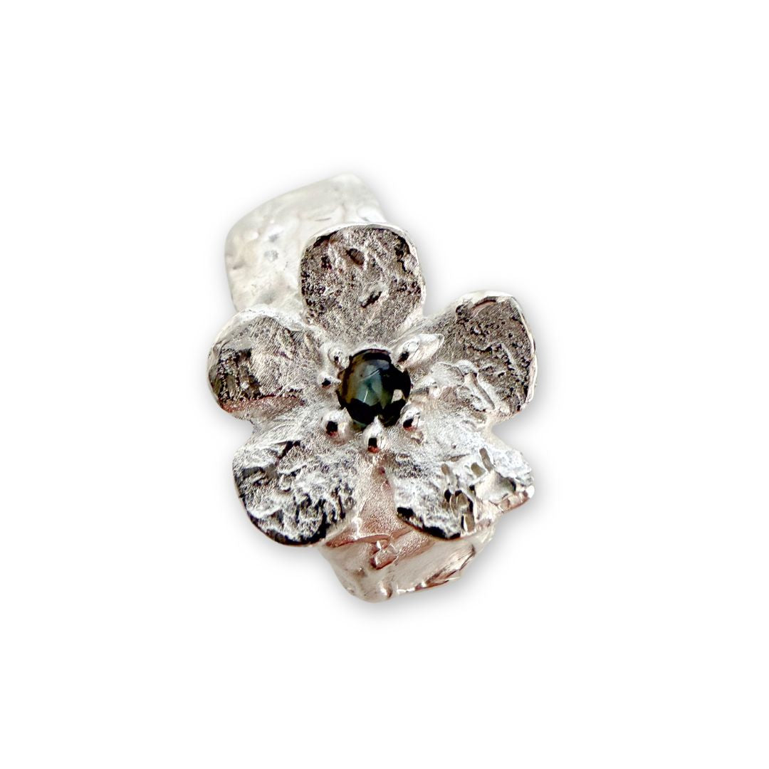Close-up of Waiatarua Wide flower ring showing the textured silver petals and 3mm deep blue cabochon sapphire.