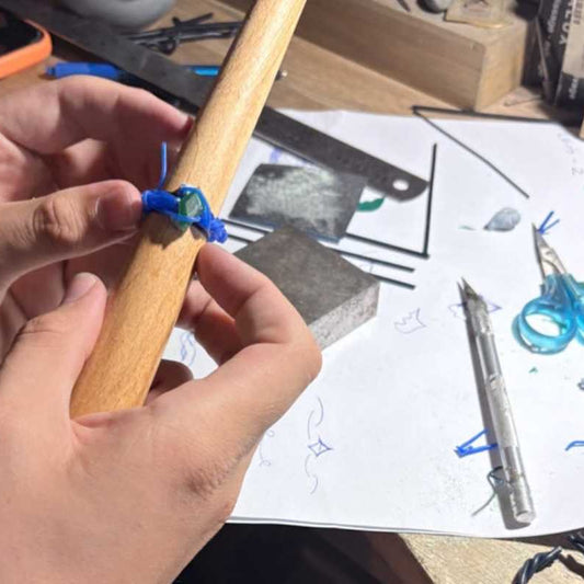 Working with blue wax wires and hand carving techniques to design a custom wax jewel during an Auckland workshop.