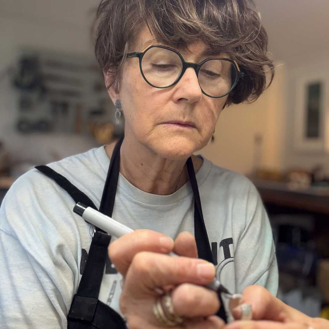A female Jewellery maker and designer marking out the centre line on a hoop earring ready to place the ear post