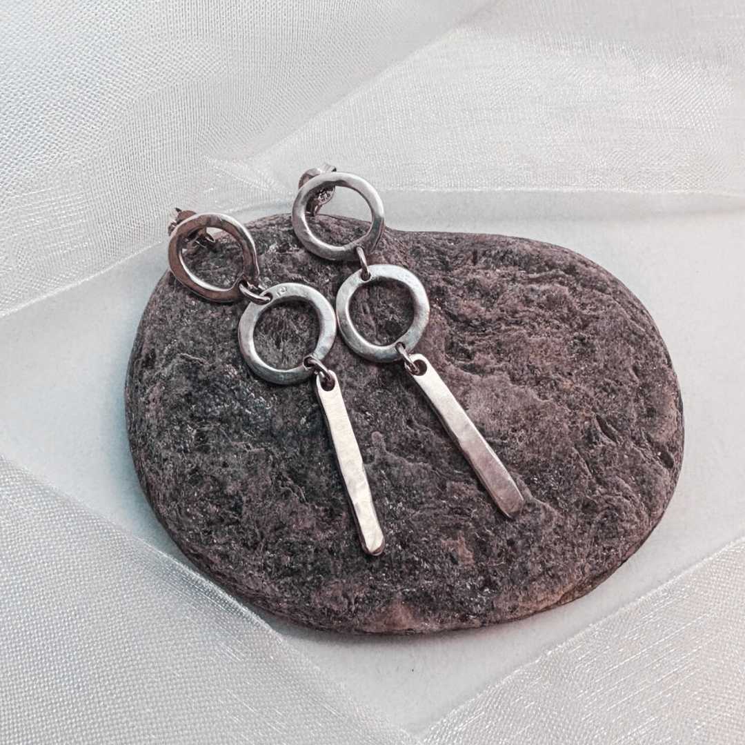 Abstract Circle Earrings No. 25 in sterling silver resting on a textured stone, surrounded by soft white organza ribbon, handcrafted by HerbertandWilks