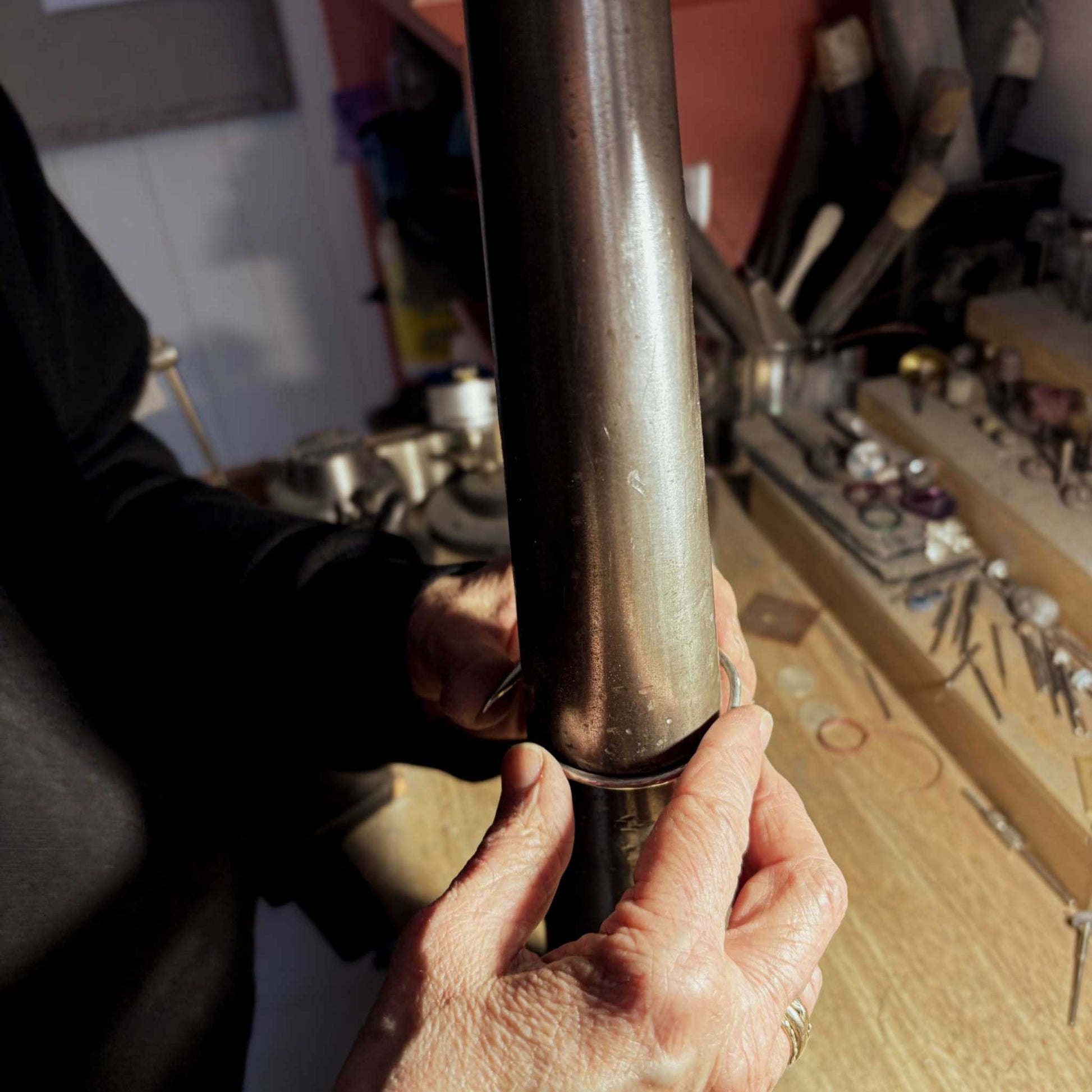 Hands bending sterling silver wire around a steel mandrel to form the Maker Cuff during the jewellery workshop in Mt Eden, Auckland