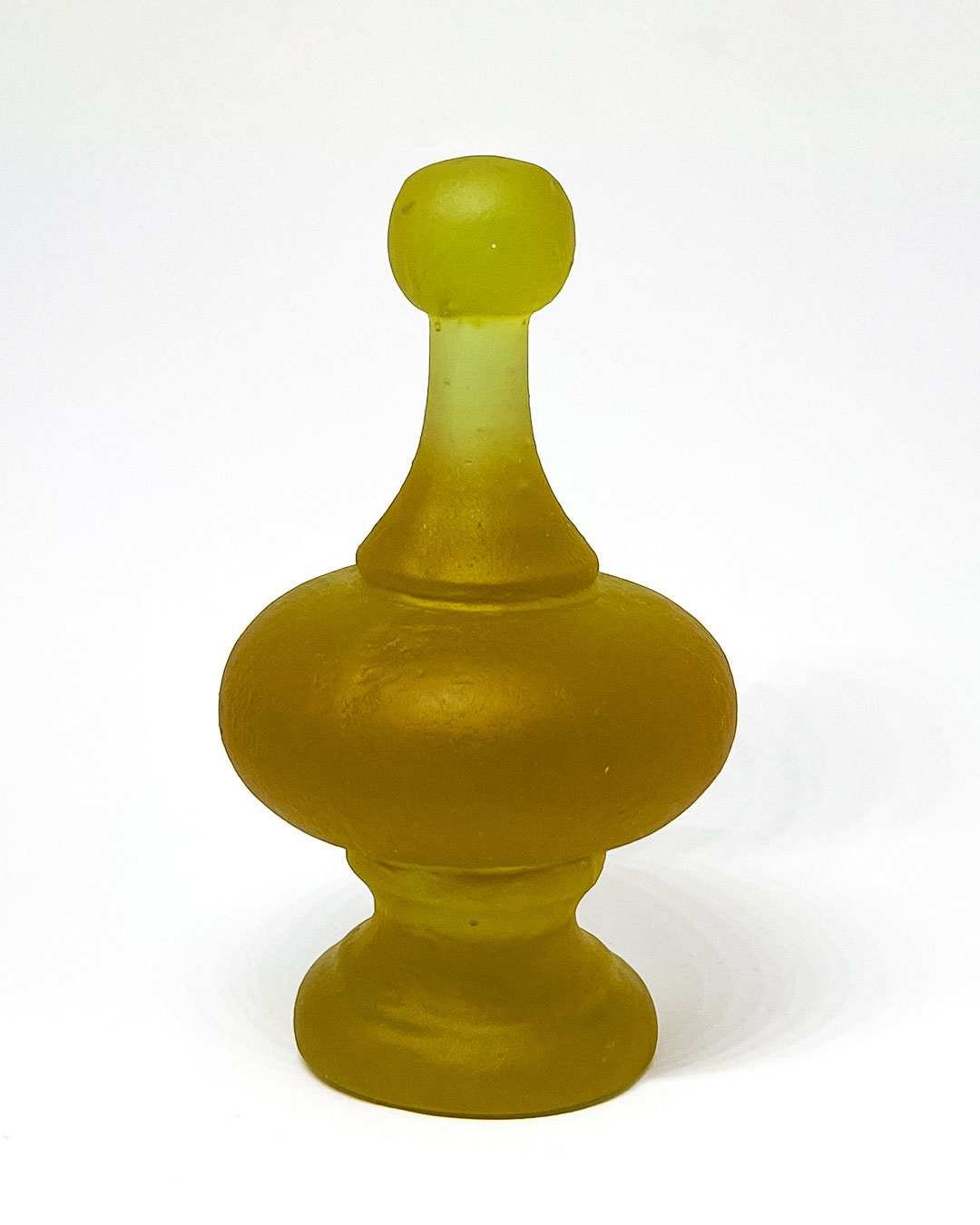 Cast glass finial sculpture showing green hue under LED lighting, set against a white background to highlight its colour shift and smooth curves.