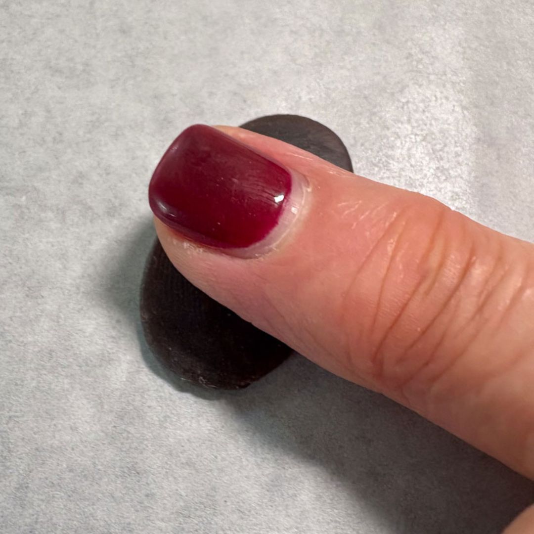 Finger pressing into wax disc to create fingerprint texture for charm