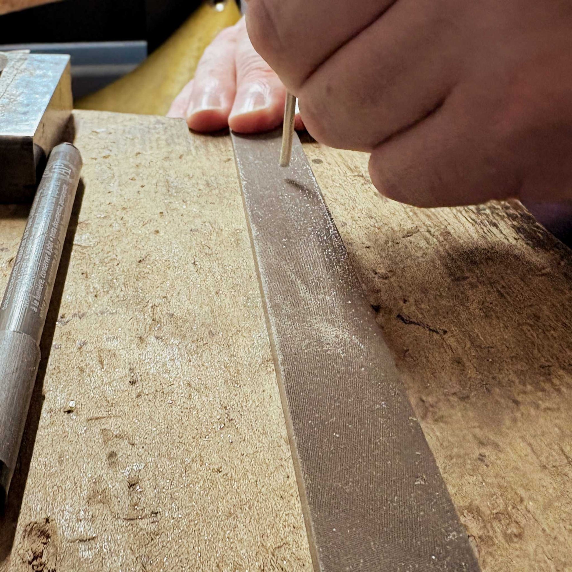 Close-up of hands smoothing the ends of a sterling silver cuff wire with a file during the Maker Cuff Workshop in Mt Eden, Auckland