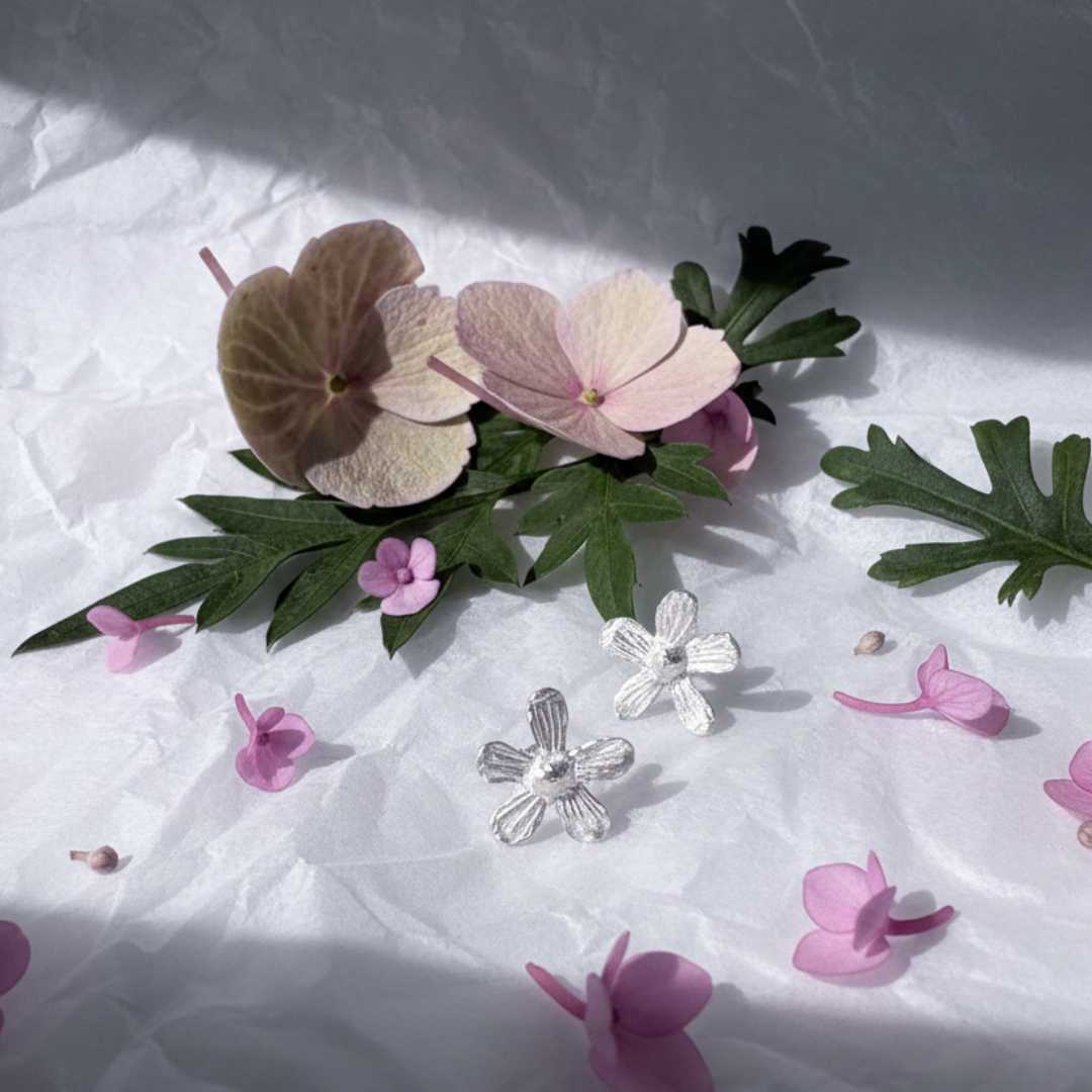 Flora sterling silver stud earrings styled with fresh flowers showing nature-inspired petal design