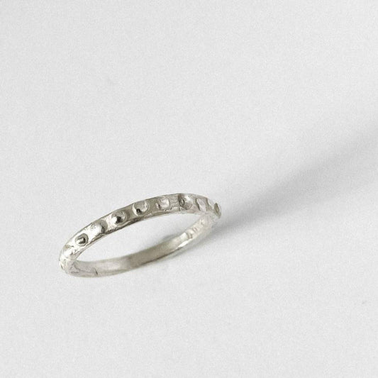 Top view of Fluid 2mm raindrop textured stacking ring on grey background showing organic dot pattern