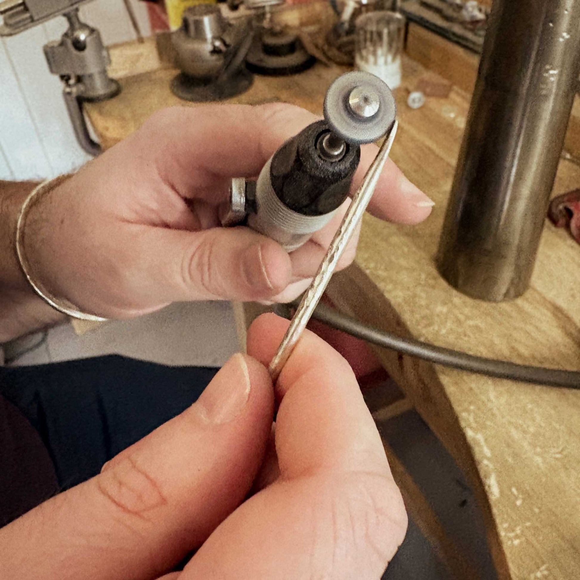 Hands using a Foredom hanging motor to polish the ends of a sterling silver cuff wire during the Maker Cuff Workshop in Mt Eden, Auckland