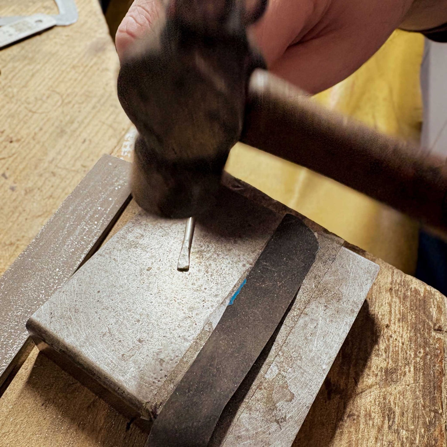 Close-up of a hammer shaping the ends of a sterling silver cuff wire during the Maker Cuff Workshop in Mt Eden, Auckland