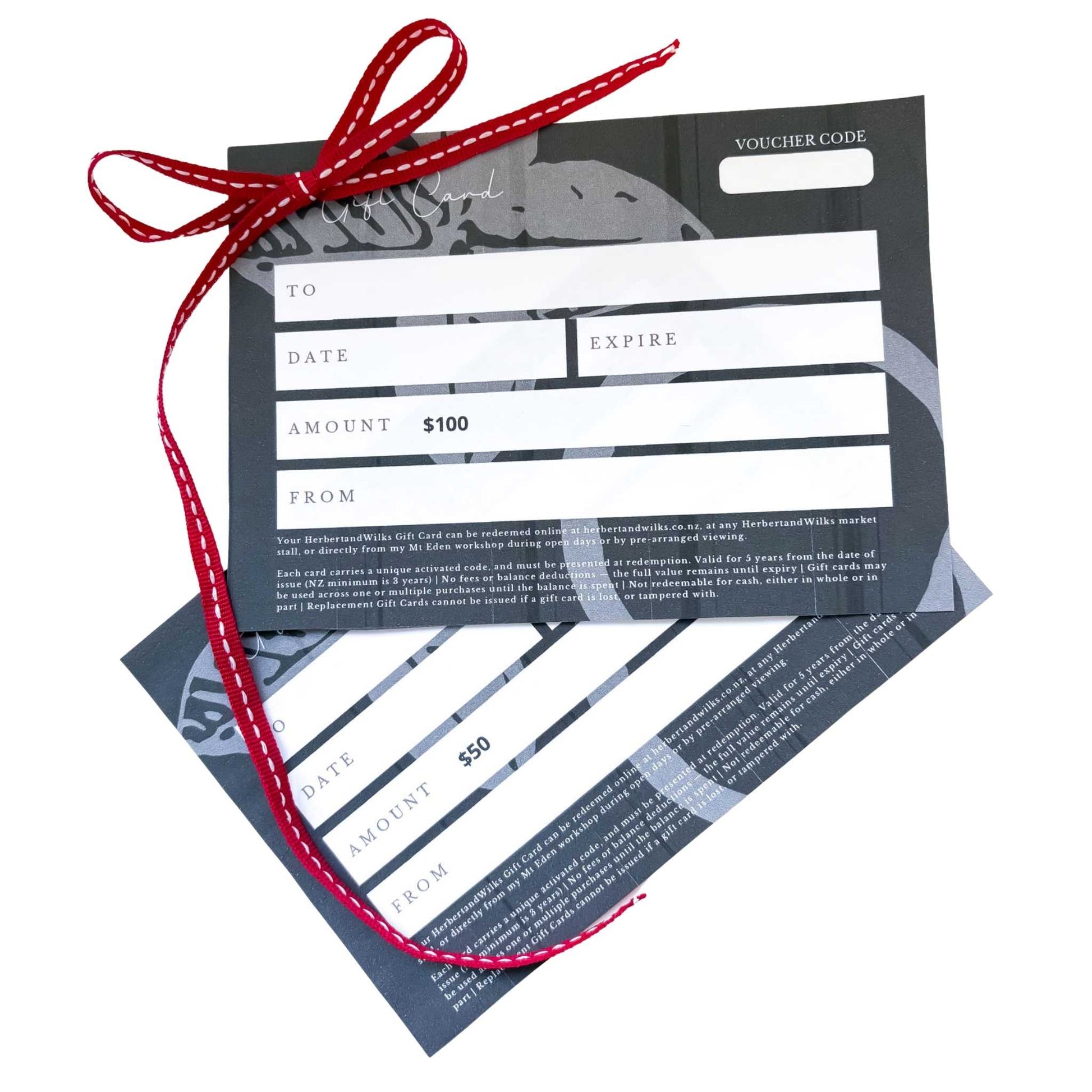 Two HerbertandWilks Jewellery Gift Cards with a red ribbon curl — elegant lifestyle image for NZ jewellery gifting