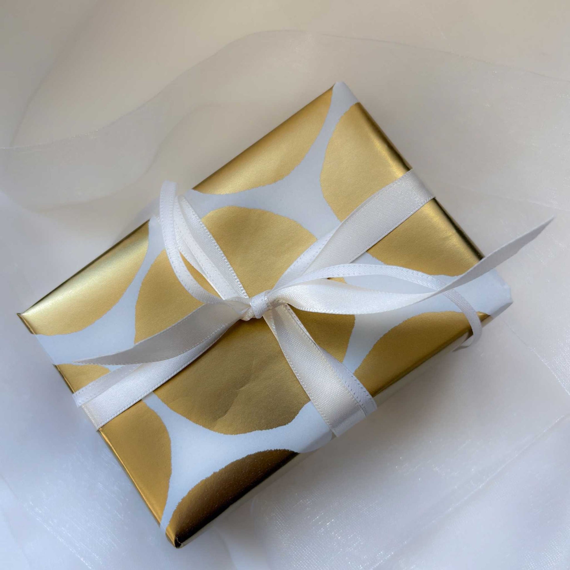 Top-down view of white and gold gift with tulle bow — symbolic image of giving a HerbertandWilks Jewellery Gift Card