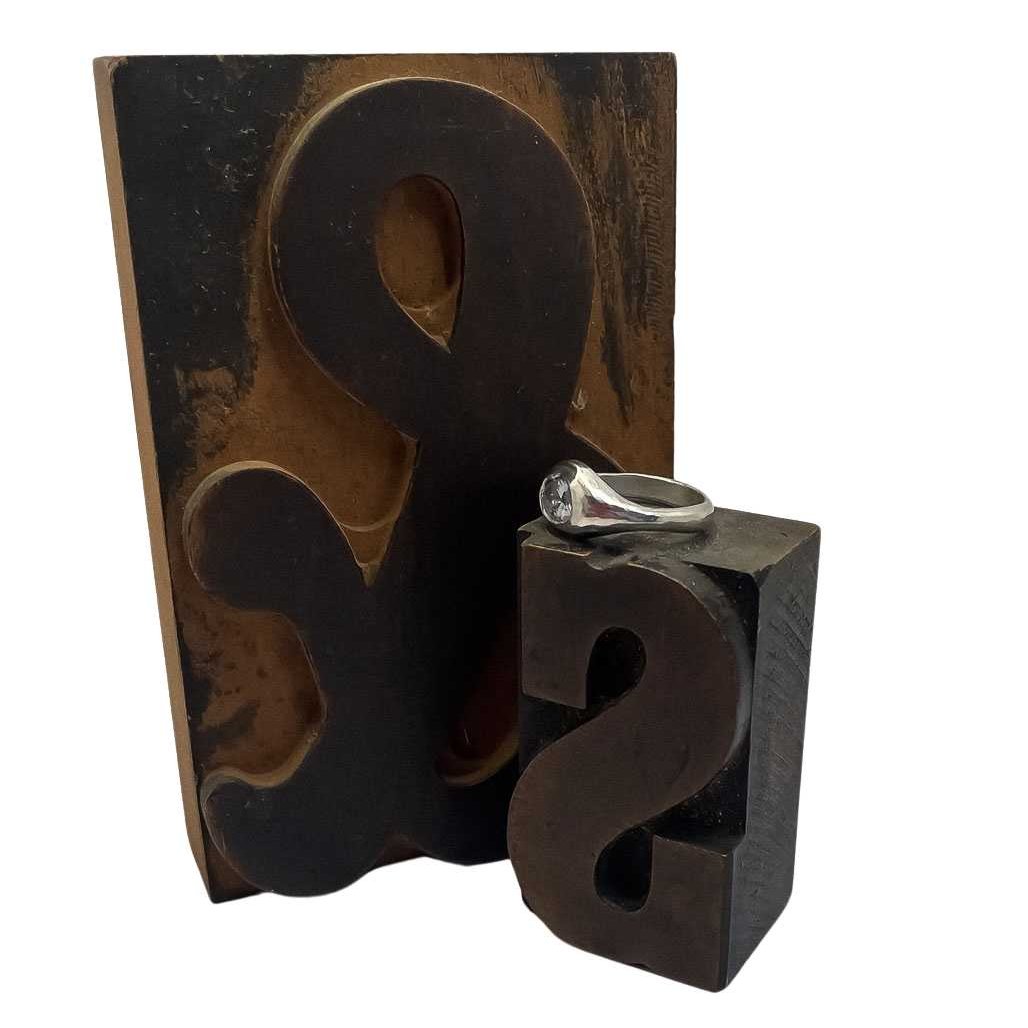 Sitting on a printers block is a Kamahi Signet Ring in Solid Sterling Silver featuring a  Blue Sapphire showing the side profile of the ring and the organic curves of the ring
