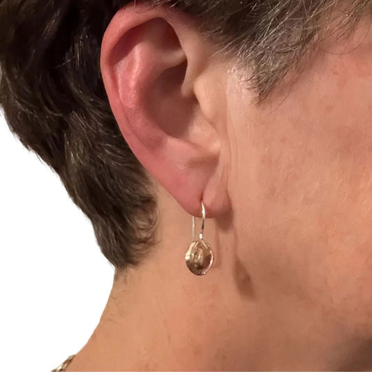 Woman wearing bronze kowhai pod earrings side profile showing drop length and everyday wearability