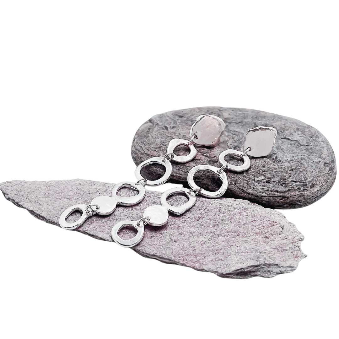 Organic Circle Trail Earrings in sterling silver – Front-facing view of the pair lying alongside each other draped over stones against a white background.