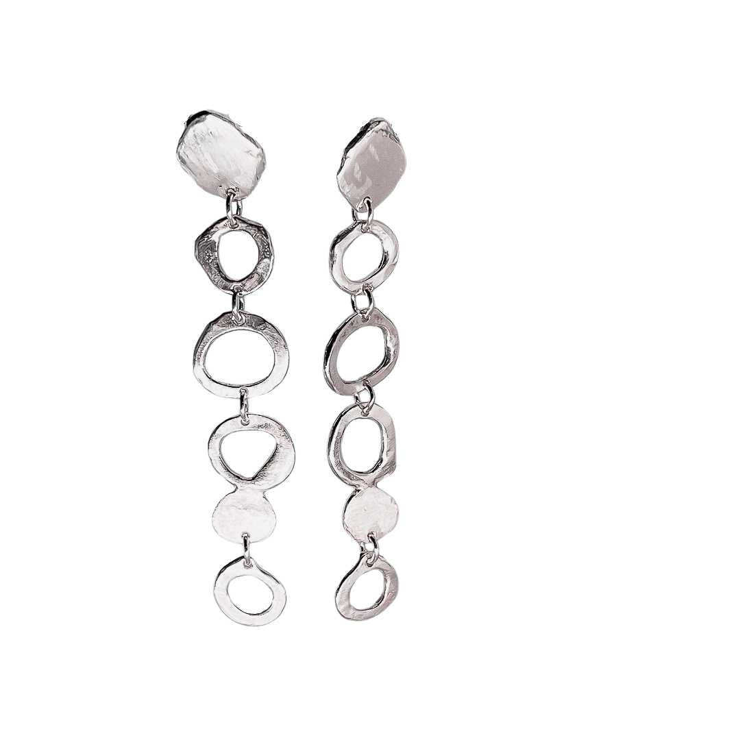 Detail view of the Organic Circle Trail Earrings highlighting the unique wax-cast textures and the rhythmic mix of solid and outline circle forms.