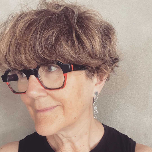 Artistic lifestyle shot of the Organic Circle Trail Earrings being worn, showing the 58mm length and swaying style on a model looking to the left.