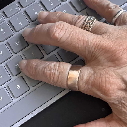 Wide band organic ring in 9ct yellow gold worn on hand while typing on keyboard, showing comfortable everyday wear and satin finish