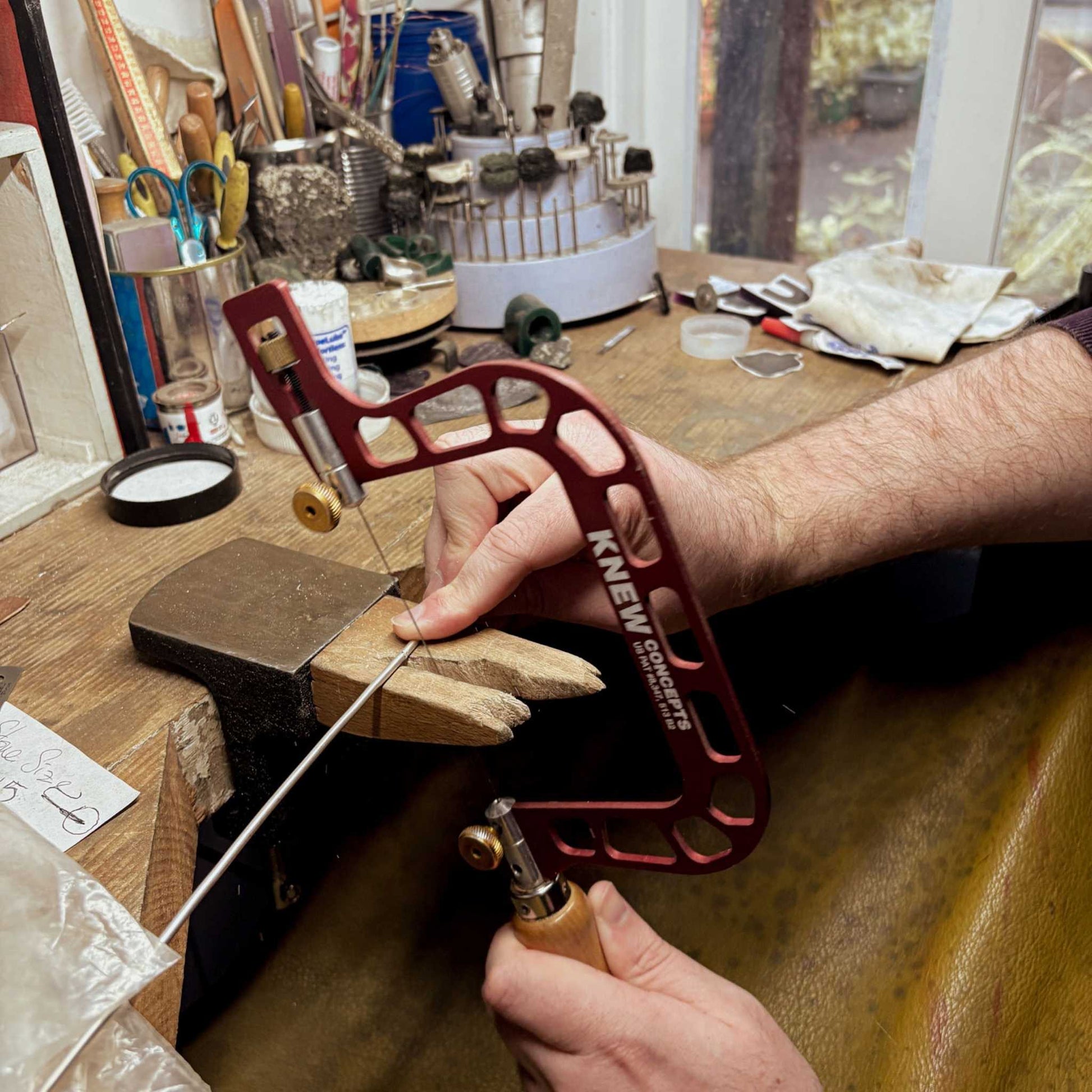 Close-up of hands using a jeweller’s saw to cut sterling silver for the Maker Cuff Workshop at a workbench in Mt Eden, Auckland