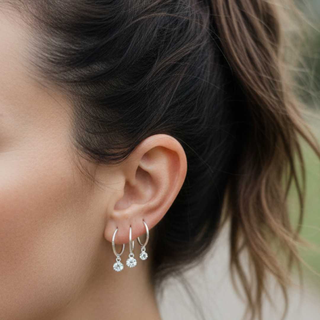 Woman wearing three sterling silver sleeper earrings showing 16mm 14mm 12mm size comparison with diamond charms