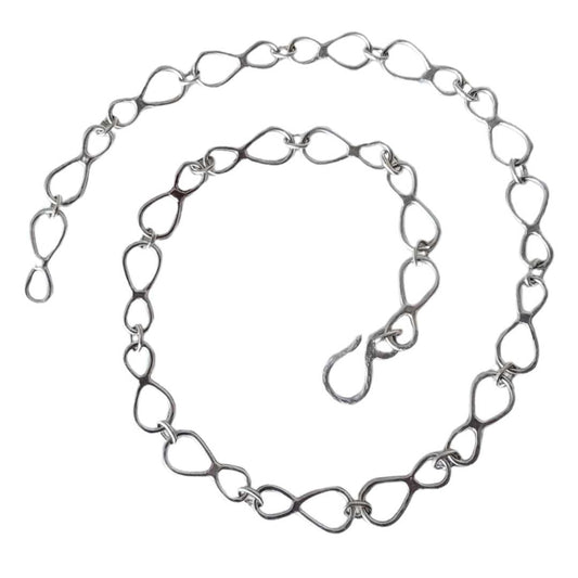 Still Loop sterling silver chain necklace coiled in a spiral on a white background.