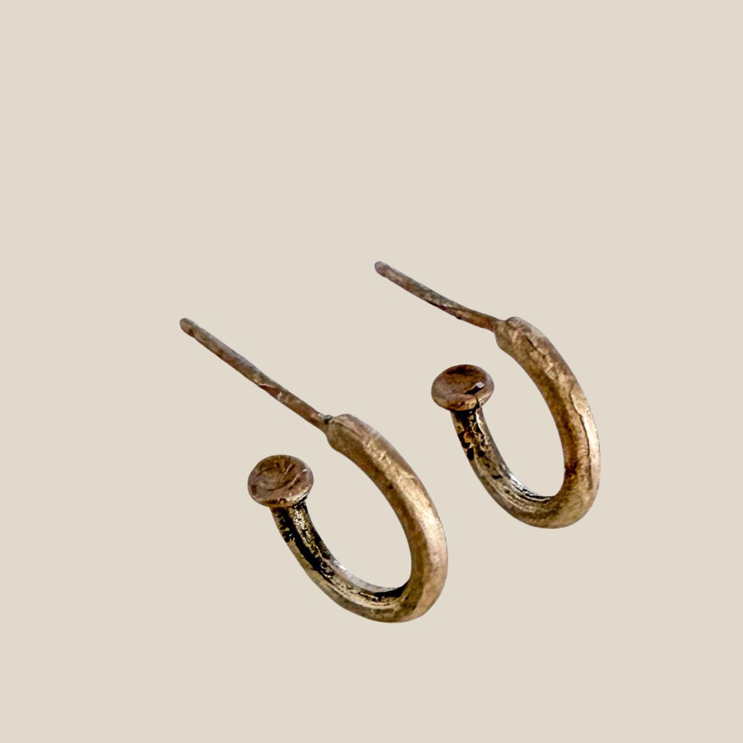 A pair of textured 9ct gold hoop earrings with mushroom-shaped tops and post-back closures, shown on a solid light beige background.