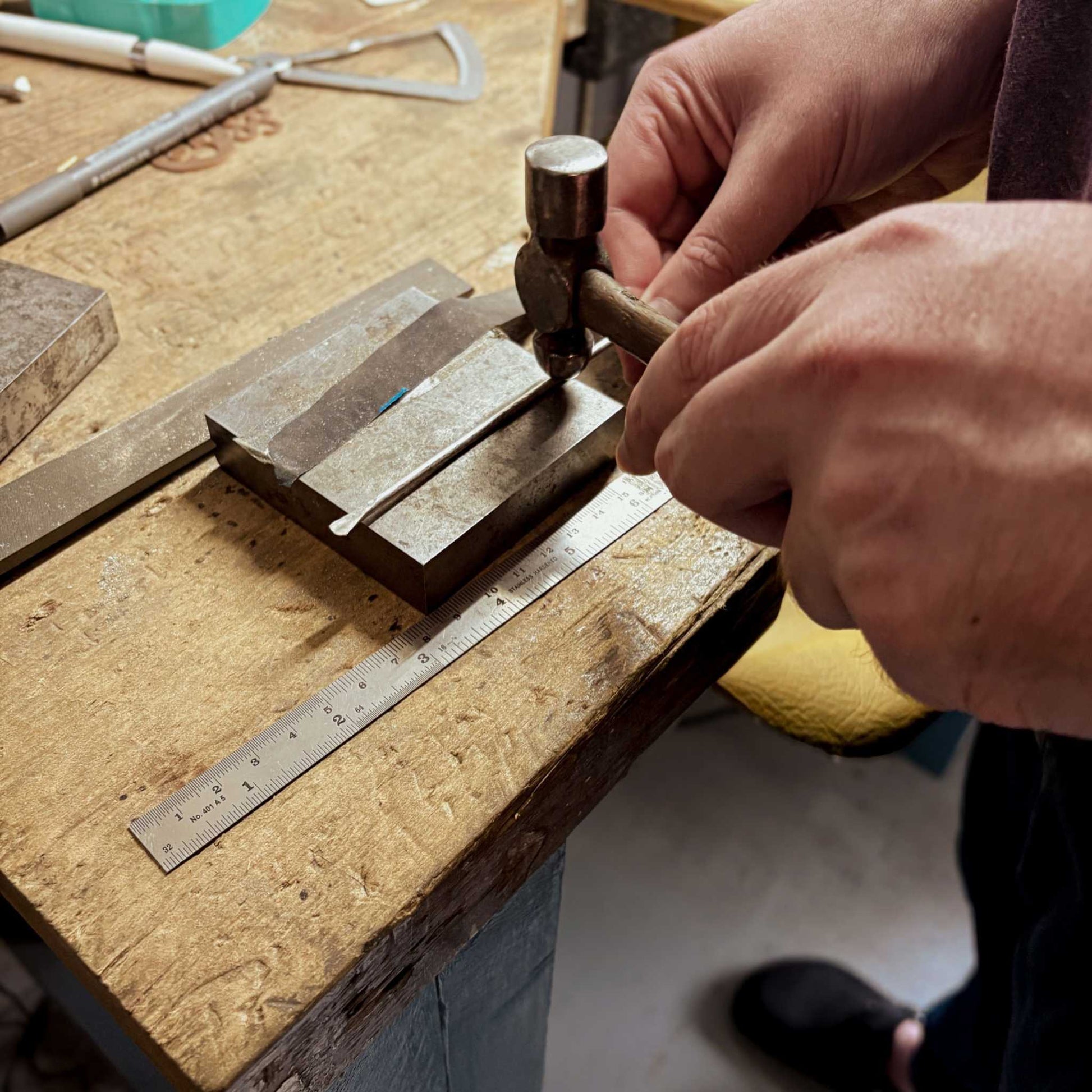 Close-up of hands applying texture along the length of a sterling silver cuff during the Maker Cuff Workshop in Mt Eden, Auckland