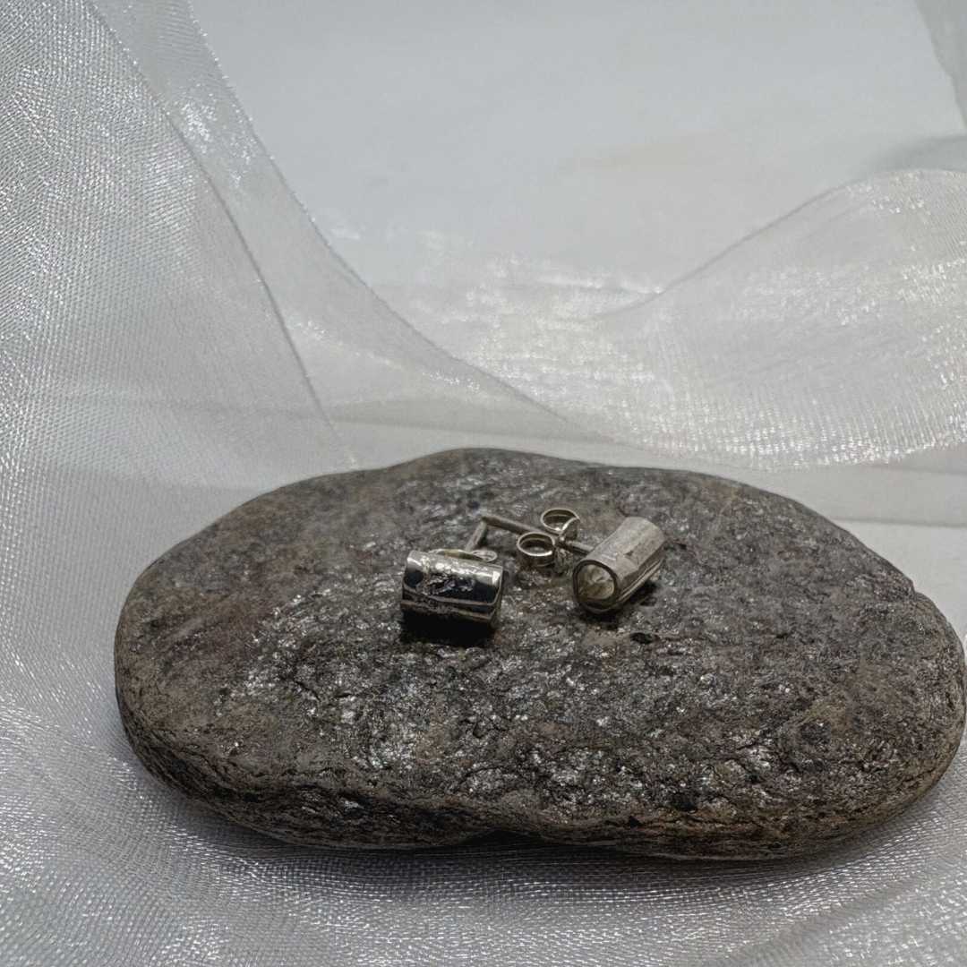 Fine silver Wrapped Mini Stud Earrings resting on textured stone with soft white organza ribbon against light grey background